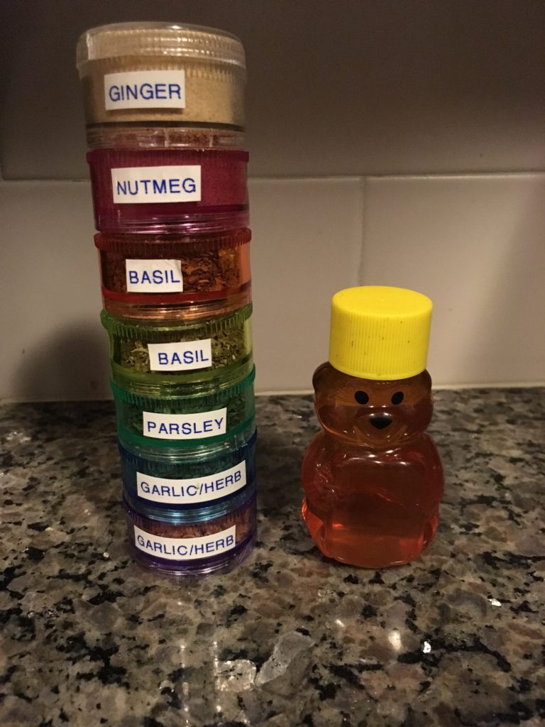 Round stacking pill container with spice labels on the left, on the right a small honey bear container