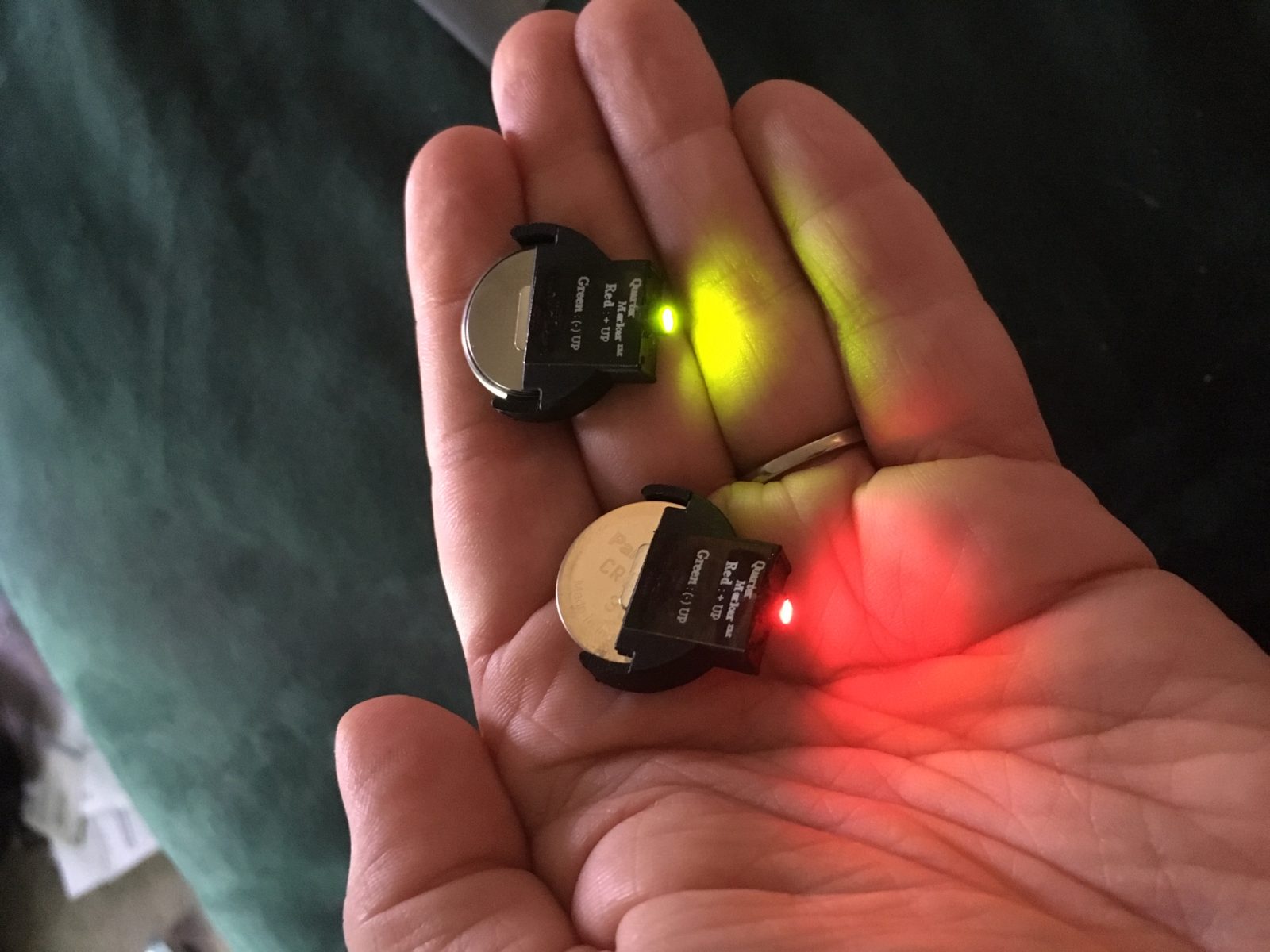 A hand holding two LED stage markers, battery operated lights in red and green