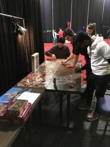 Cast and crew together work on a 1000 piece puzzle backstage.