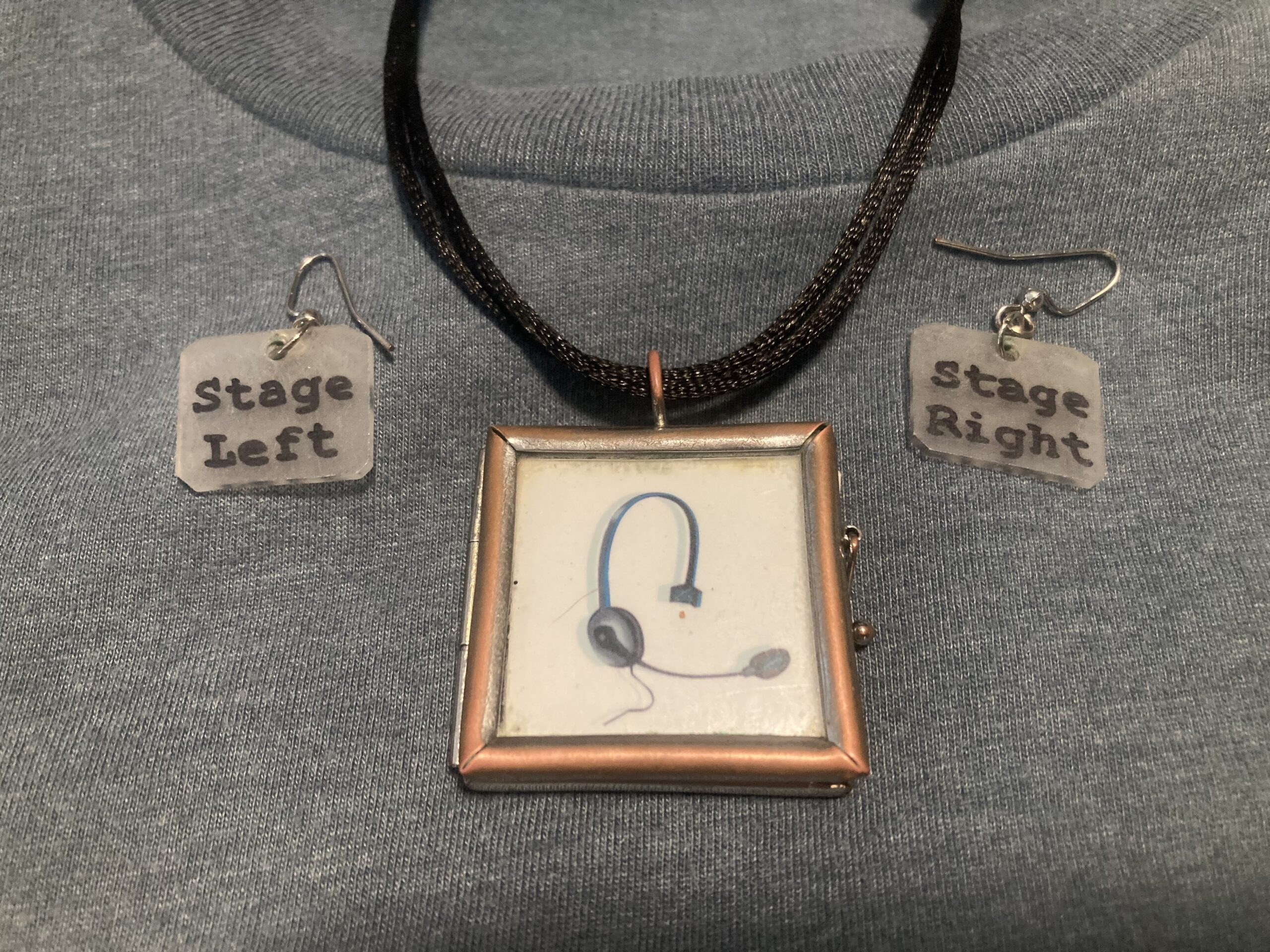 A necklace pendant of a stage management headset, and earrings that say Stage Left and Stage Right