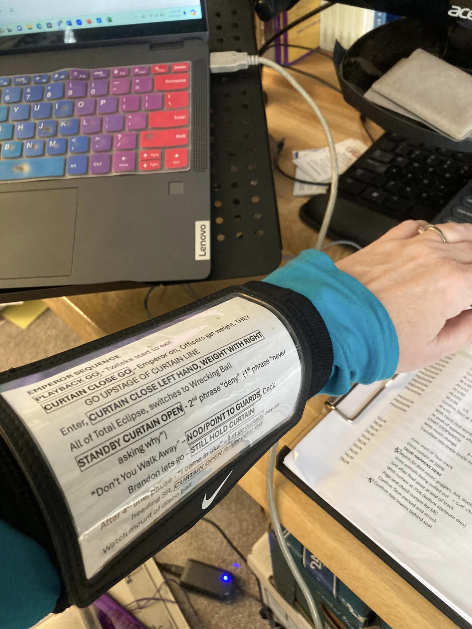 A forearm is shown at a computer desk, wearing a football quarterback type sleeve, with printed scene shift cues on it.