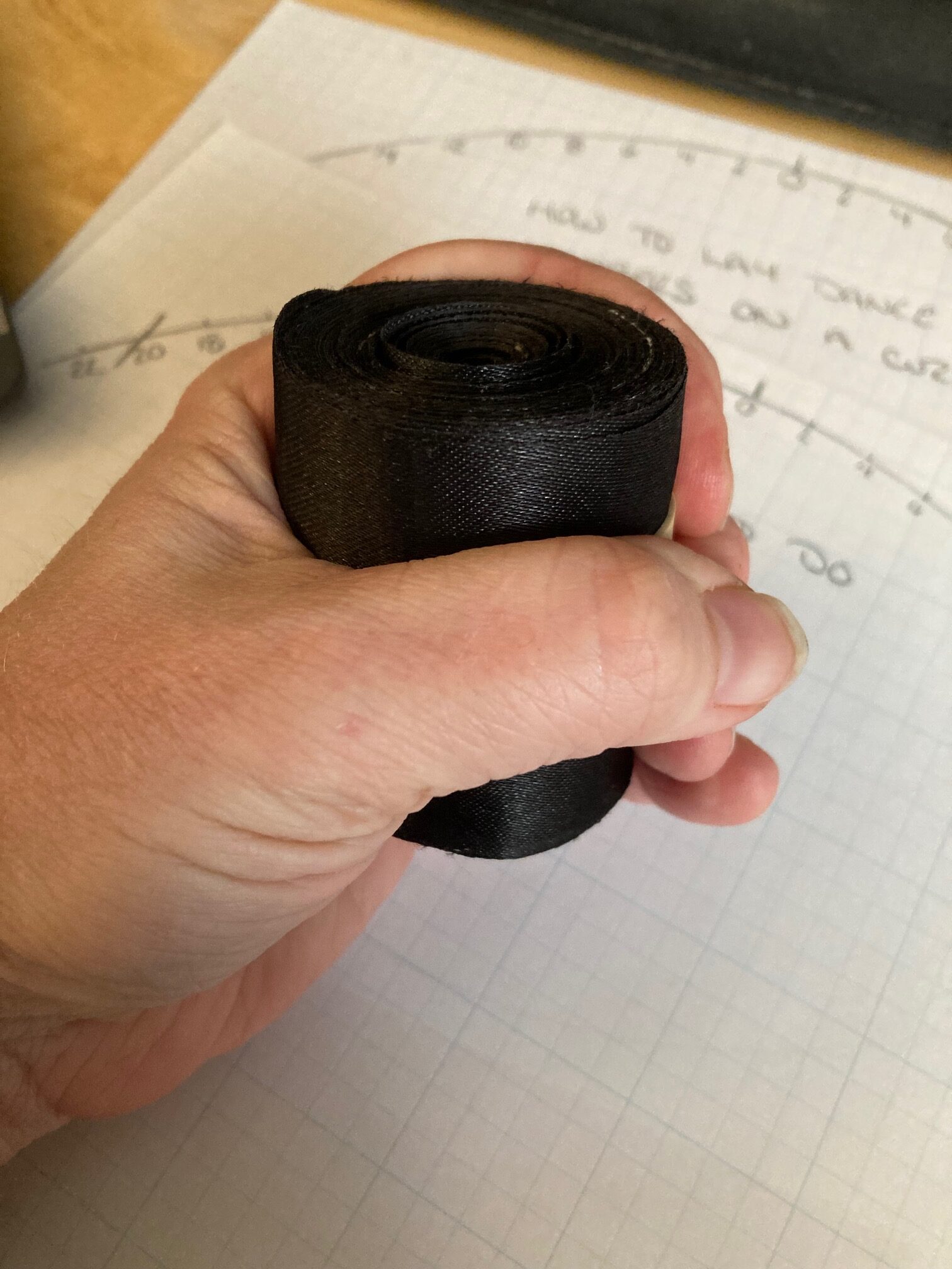 A roll of black ribbon is rolled up inside a fist