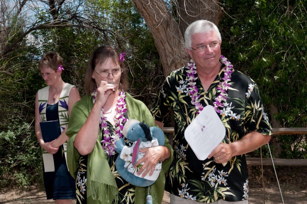 A woman plays kazoo and holds a blue Eeyore sutffed animal while a man next to her looks a bit uncomfortable