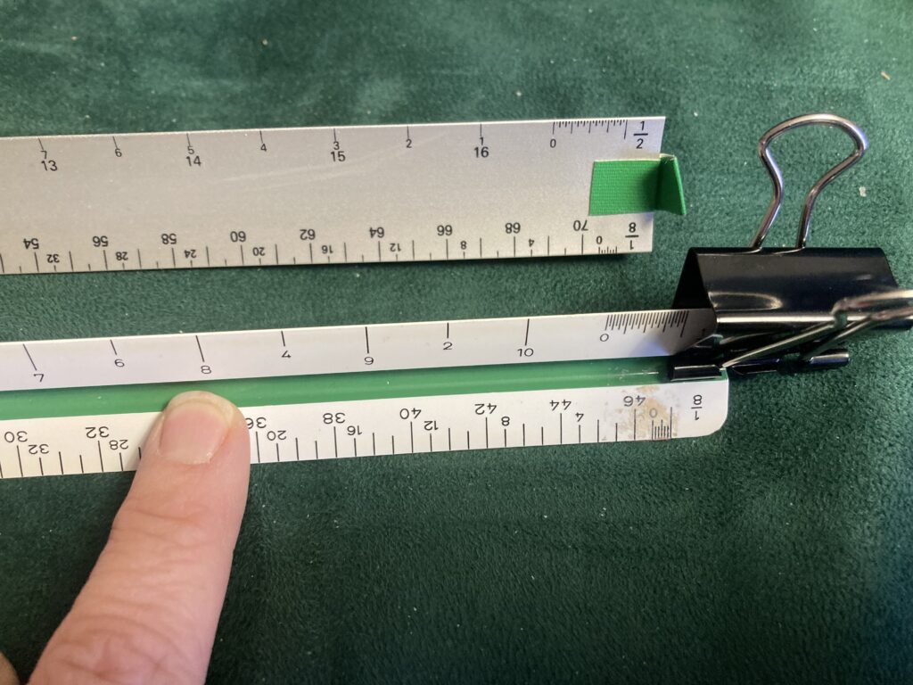 A finger points at the confusing location of the 5 vs the 8 when reading a half inch scale ruler